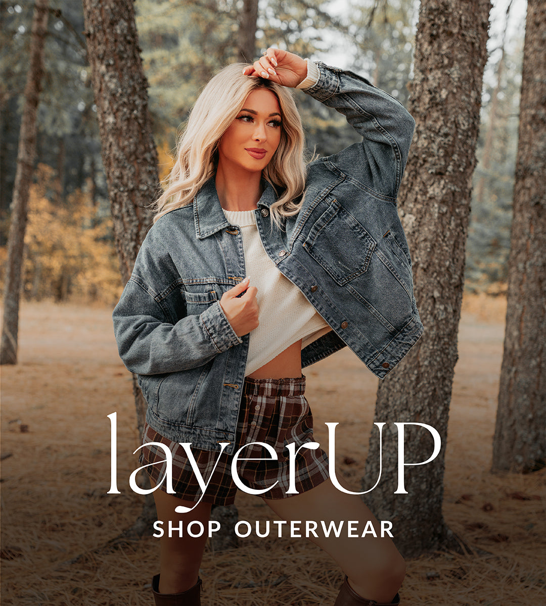 Woman in a forest wearing a denim jacket with 'layerUP' branding.