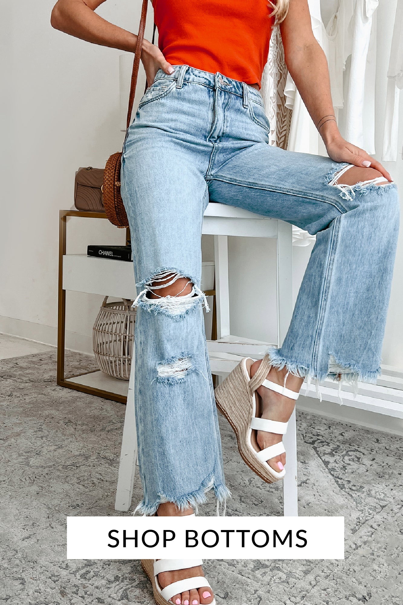 Model wearing distressed light wash denim with an orange bandeau top and white strappy wedges. Call to action says "Shop Bottoms" and links to the bottoms collection.