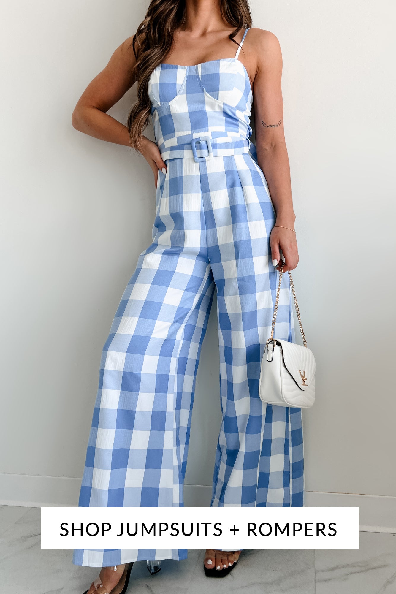 Model wearing a gingham print belted jumpsuit. Call to action says "Shops Jumpsuits + Rompers" and links to the Jumpsuits and Rompers Collection.