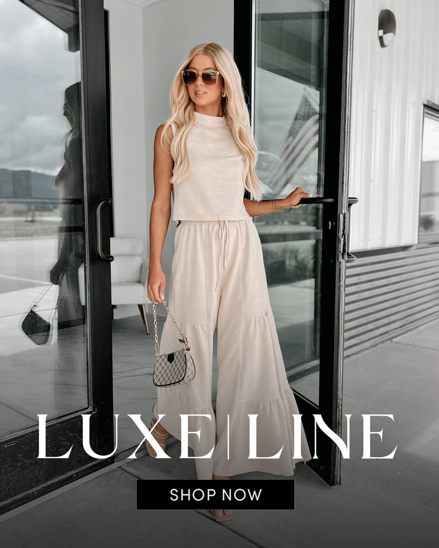 Photo of a model wearing a beige flowy pants set. Headline says "Luxe Line" elevate your wardrobe with timeless silhouettes in classic neutral tones. Links to the Lux Line.